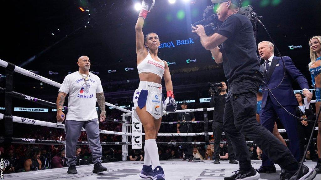 Amanda Serrano raises her fist as she enters the boxing ring