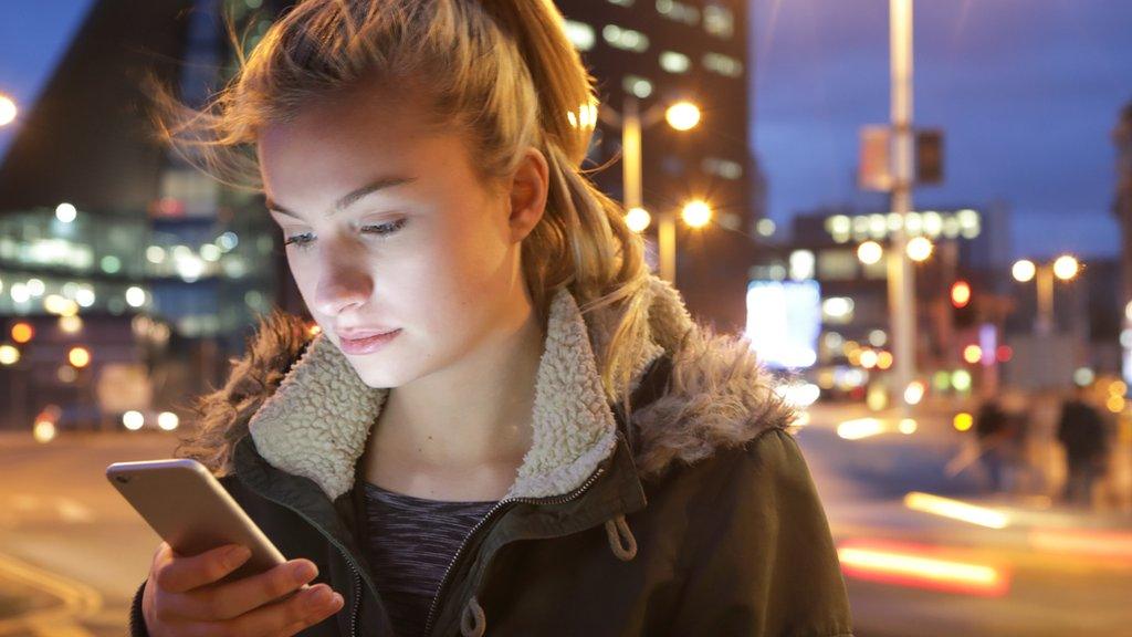 A stock photo of a young woman looking at a phone