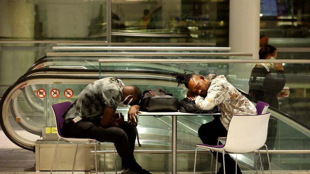 Two travellers sleep at the airport