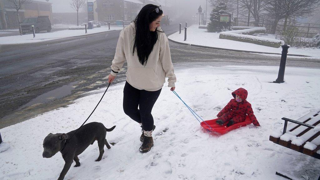 A woman pulls a child through the snow on a sledge