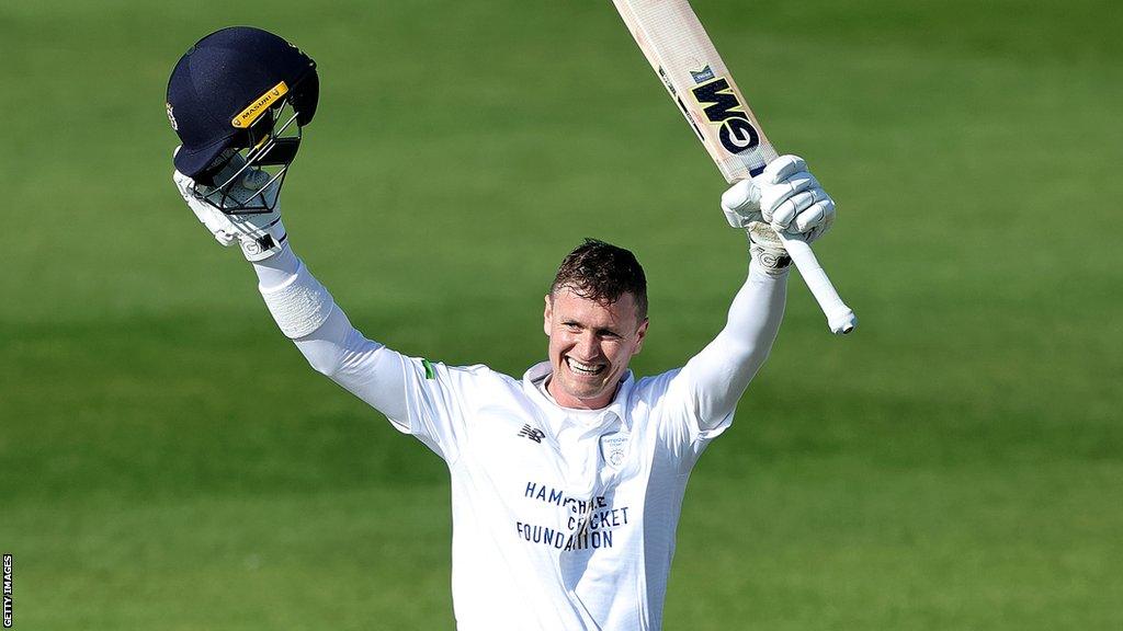 Nick Gubbins raises his helmet and bat in the air