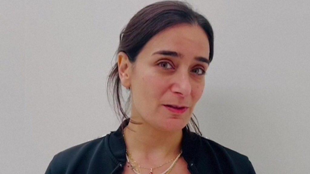 Woman with dark hair speaking to camera