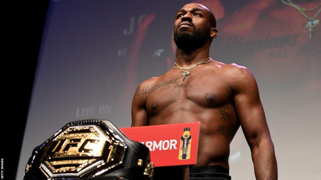 Jon Jones weighs in on the scales in front of his UFC title