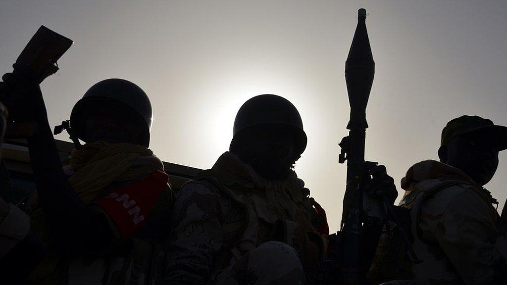 Nigerien soldiers with RPG and automatic weapons silhouetted