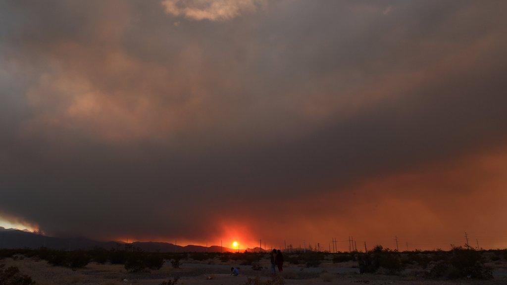 The wildfire obscures the setting sun