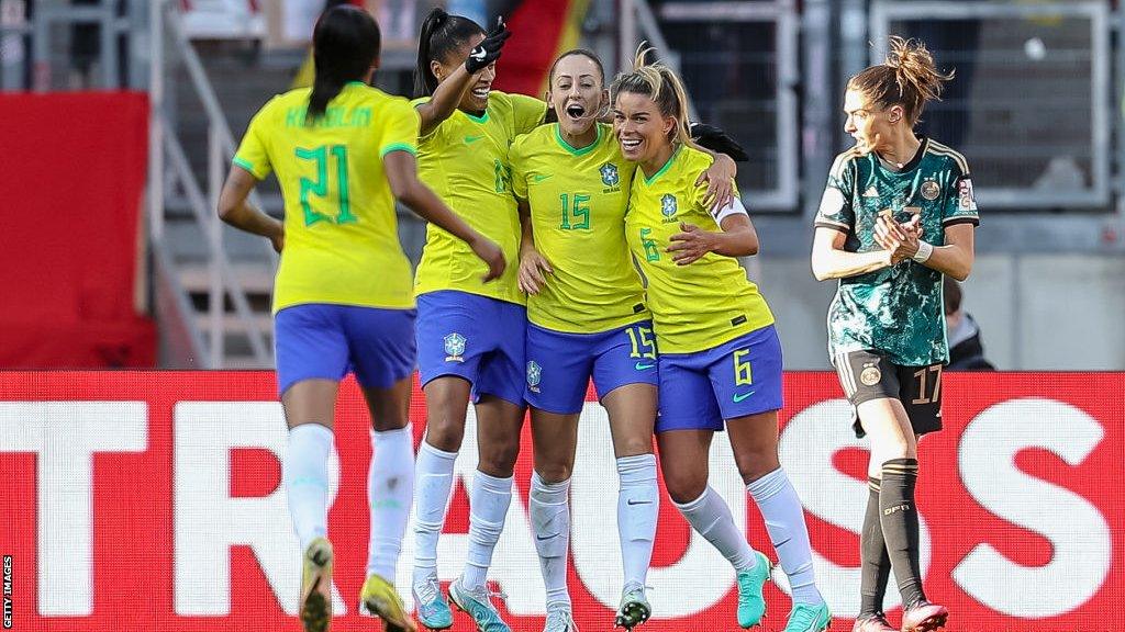 A group of Brazil players hug and celebrate scoring a goal