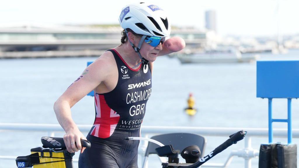 Claire Cashmore holding her bicycle while competing in a triathlon