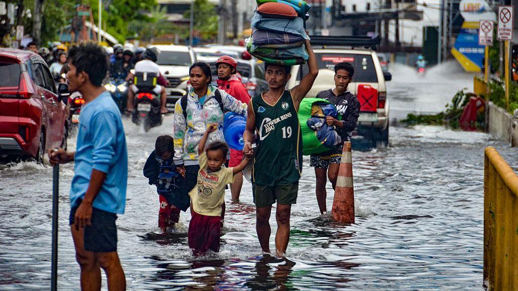 Residents carrying their belongings, wade through a flooded street in Mandaue City, Cebu province