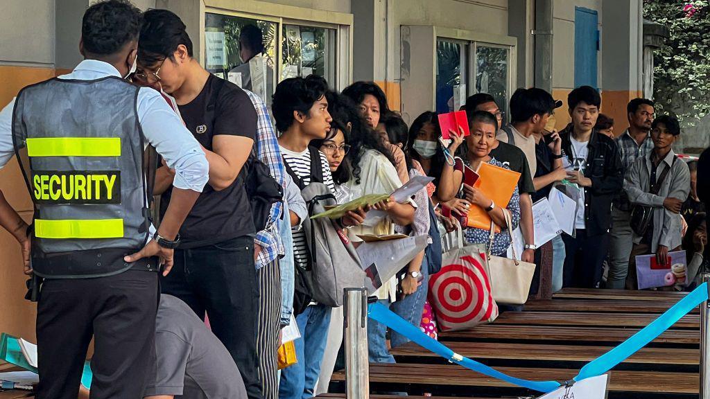 People queue to get visas in front of the embassy of Thailand in Yangon on February 16, 2024, after Myanmar's military government said it would impose military service. 