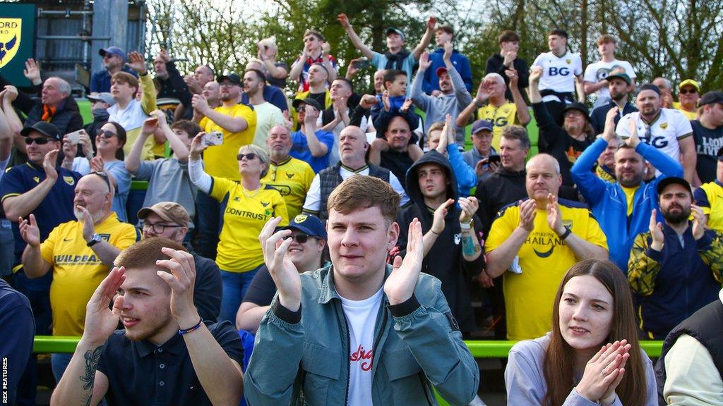 Oxford United fans cheer on their team from the stands.