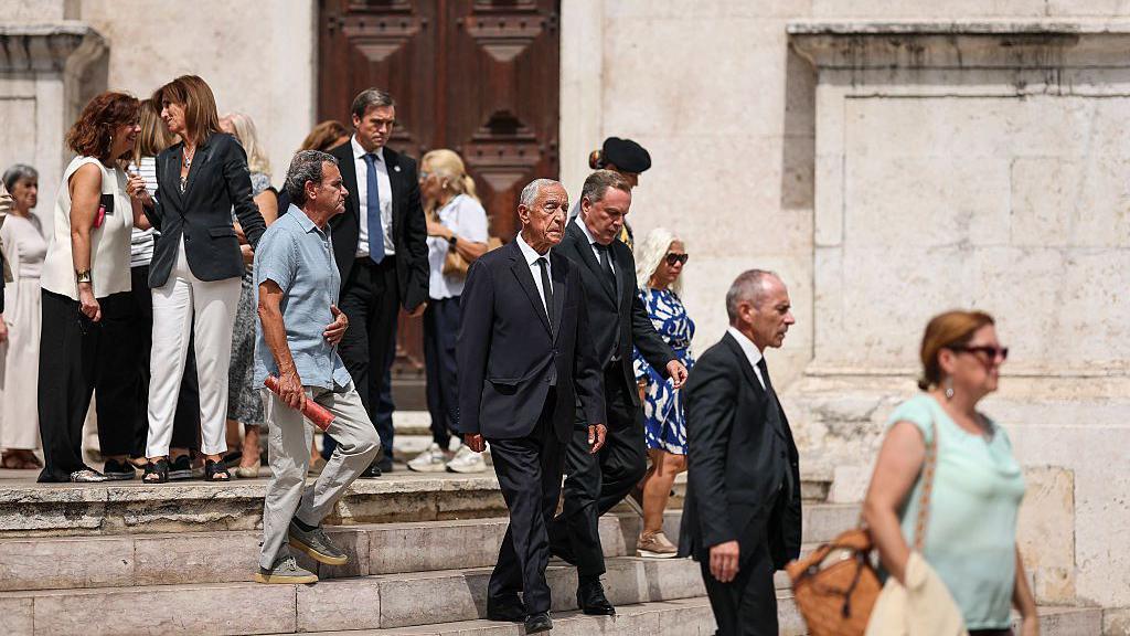 Rebelo walks down the steps at the entrance of the church with others also leaving the service