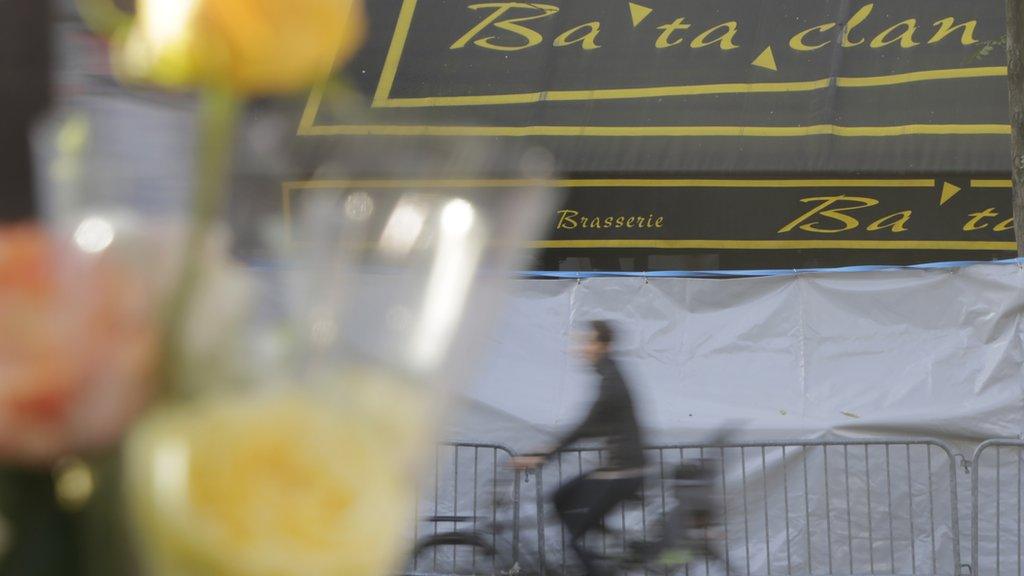 A man rides his bicycle in front of a makeshift memorial next to the Bataclan concert hall in Paris, France, Wednesday, Nov. 18, 2015