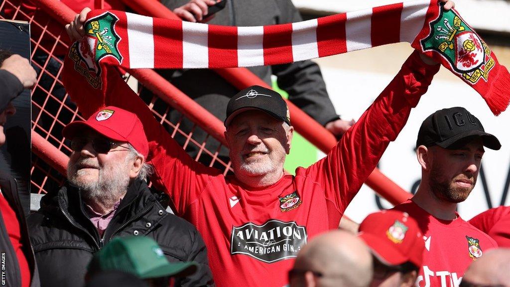 Wrexham supporter holds up a red and white scarf