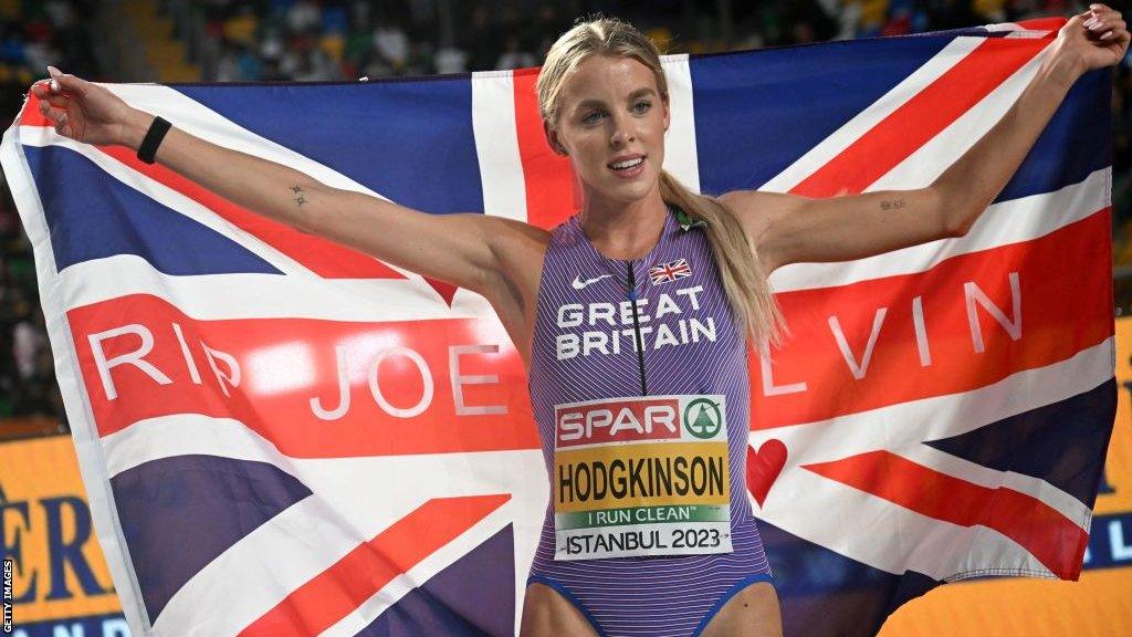 Keely Hodgkinson holds a flag in tribute to her former coach