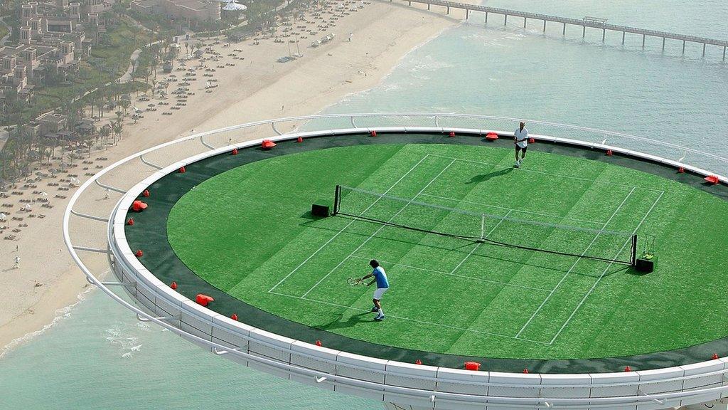 Federer and Agassi play tennis at the top of a helipad.