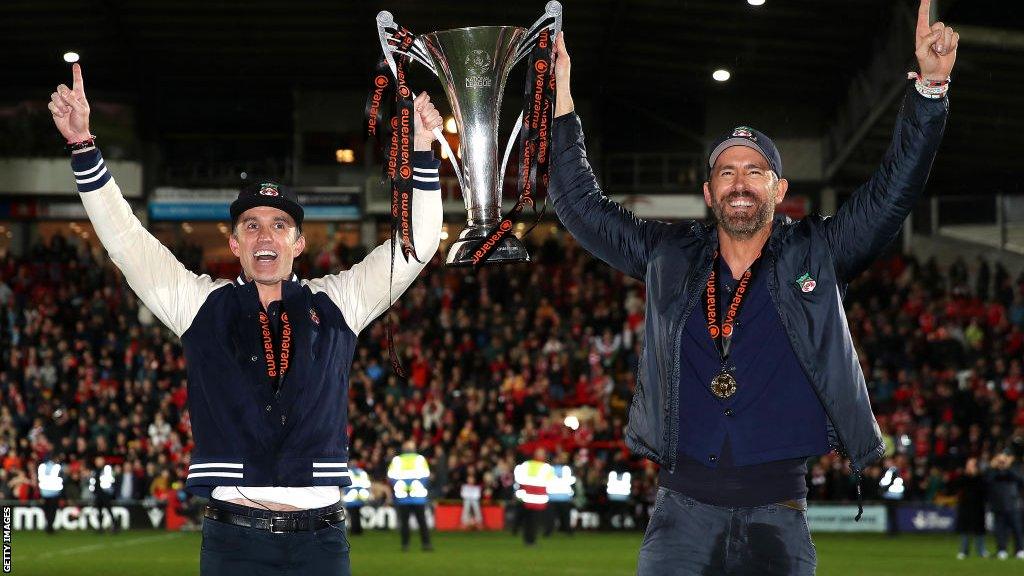 Rob McElhenney and Ryan Reynolds hold the Vanarama National League trophy