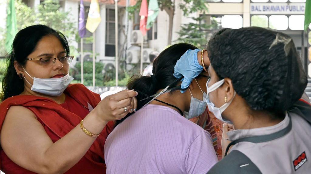 Aspirants undergo a security check before entering the exam centre as they arrive to appear for the NEET exam at Bal Bhavan Public school, on May 7, 2023 in New Delhi, India.