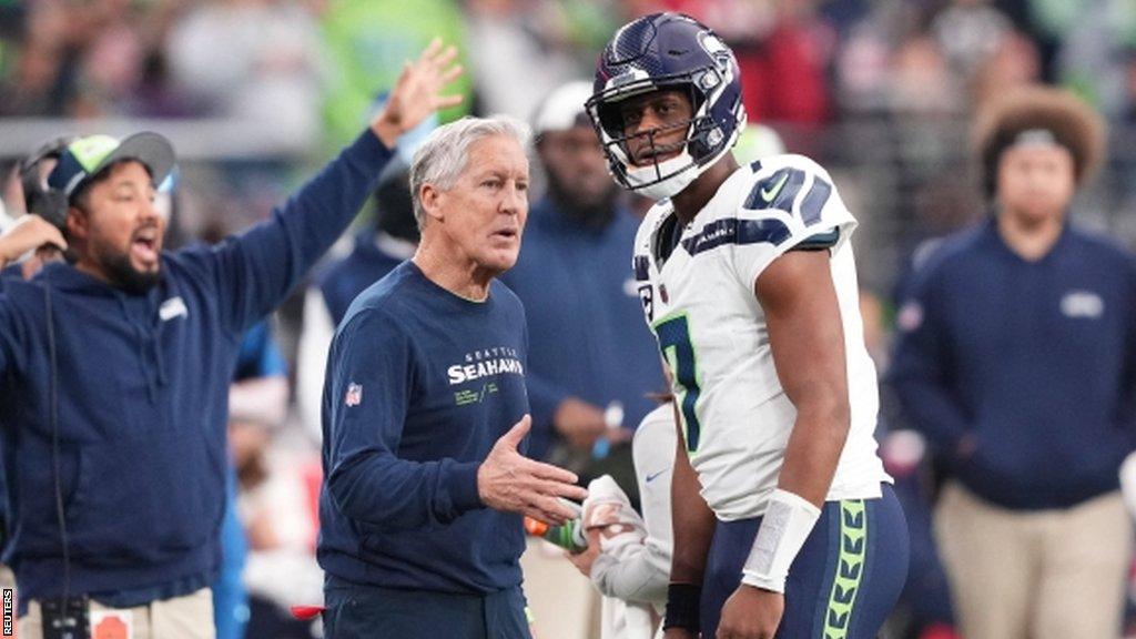 Head coach Pete Carroll talks with Seattle Seahawks quarterback Geno Smith