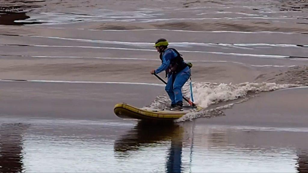 Paddleboarder riding tidal bore wave