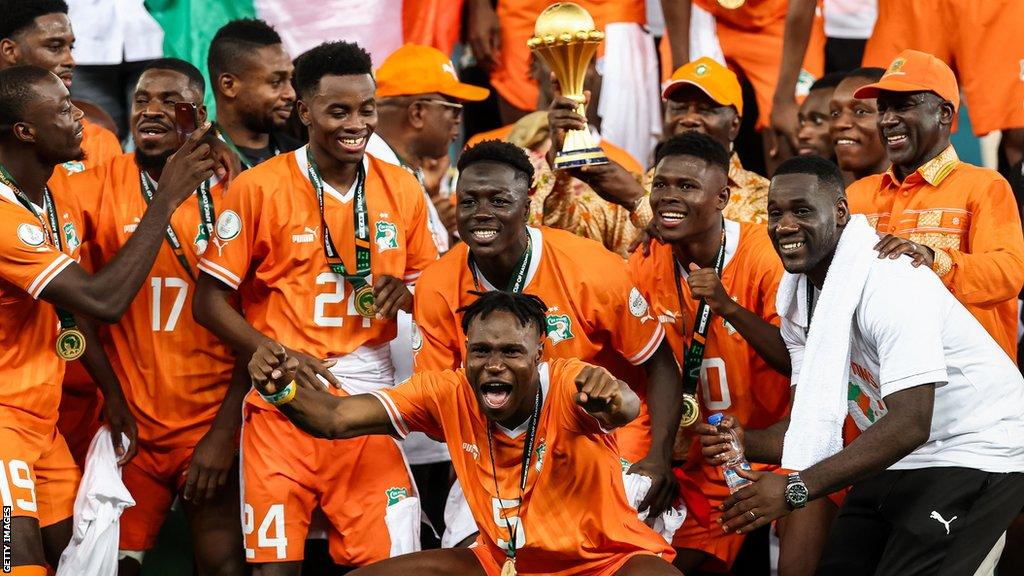 Ivory Coast players celebrate with the Africa Cup of Nations trophy after beating Nigeria