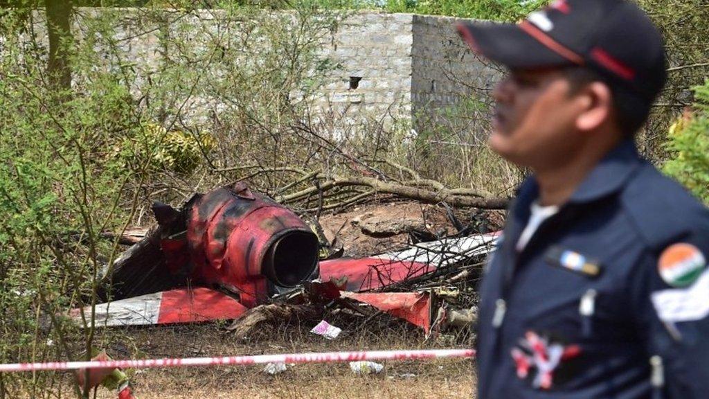 An Indian Air Force personnel walks past the wreckage of an aircraft