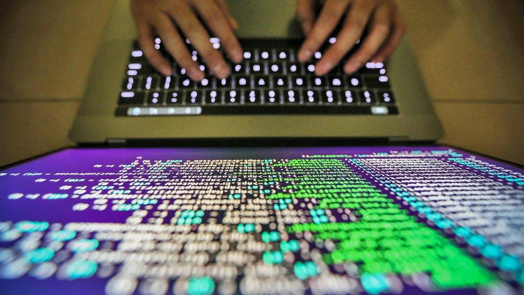 A computer programmer working on fixing Wannacry software in close up shot of screen and hands