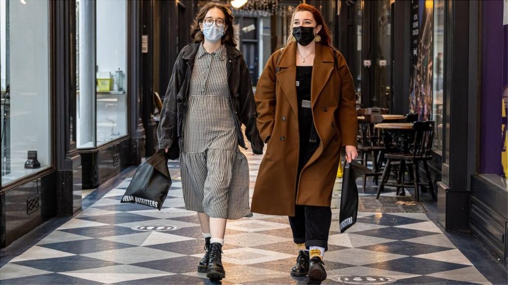 Two women walking through Cardiff wearing masks