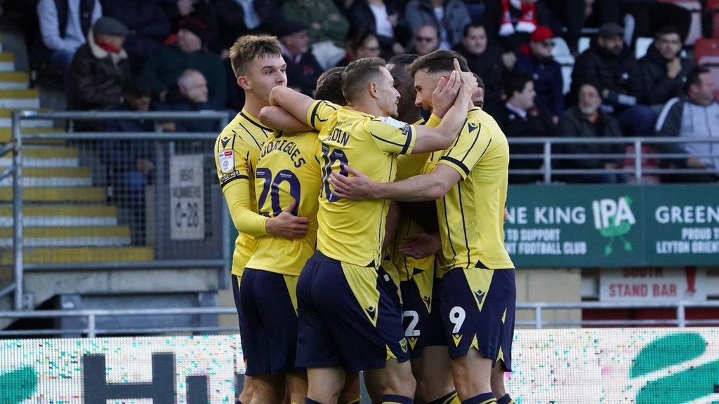 Oxford United players gather in a huddle after scoring a goal