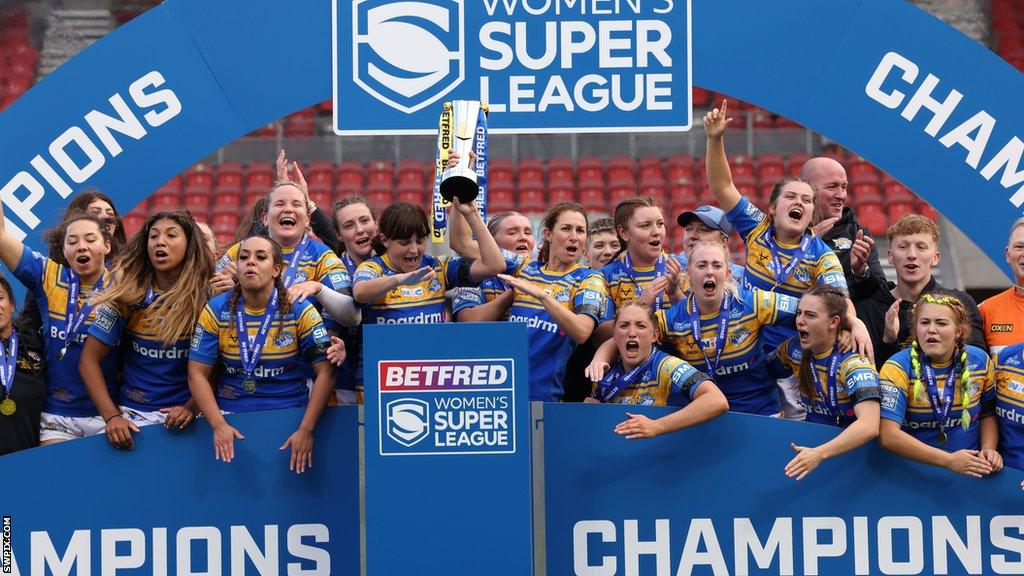 Leeds women's entire squad celebrate their 2022 Grand Final triumph by lifting the trophy aloft at the presentation