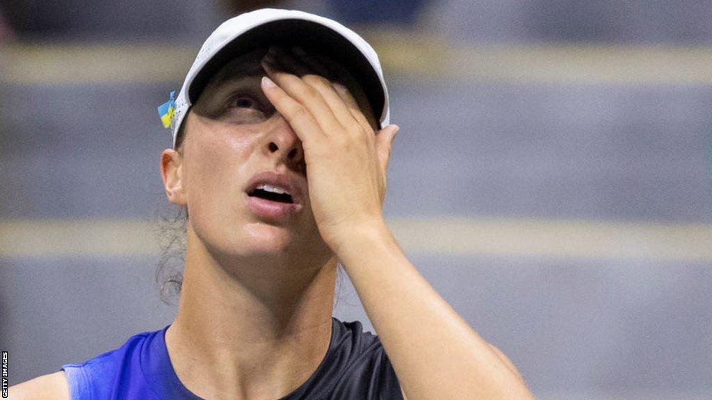 Iga Swiatek covers her face during a US Open defeat by Jelena Ostapenko