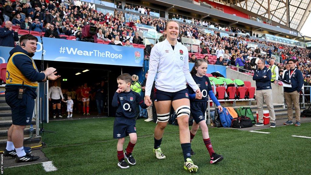 Zoe Aldcroft holding hands with two mascots