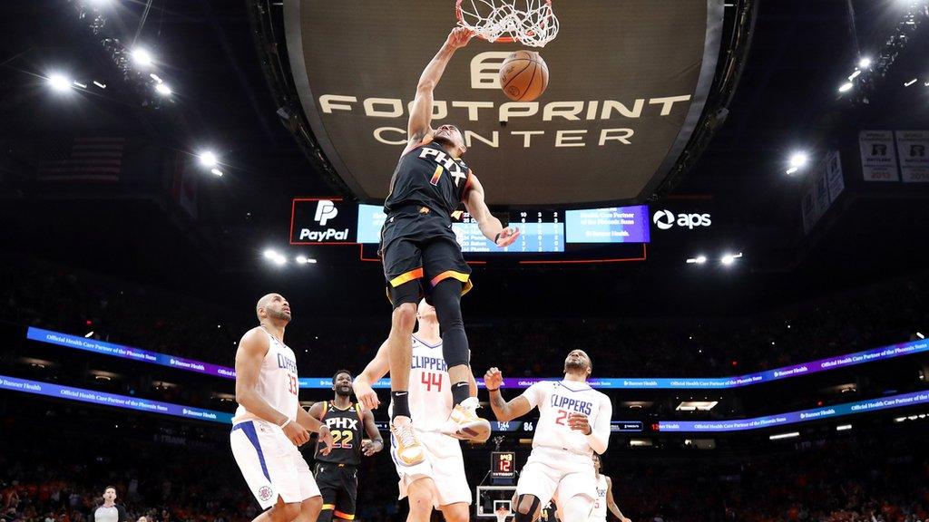 Devin Booker dunking the ball with three Los Angeles Clippers players watching on