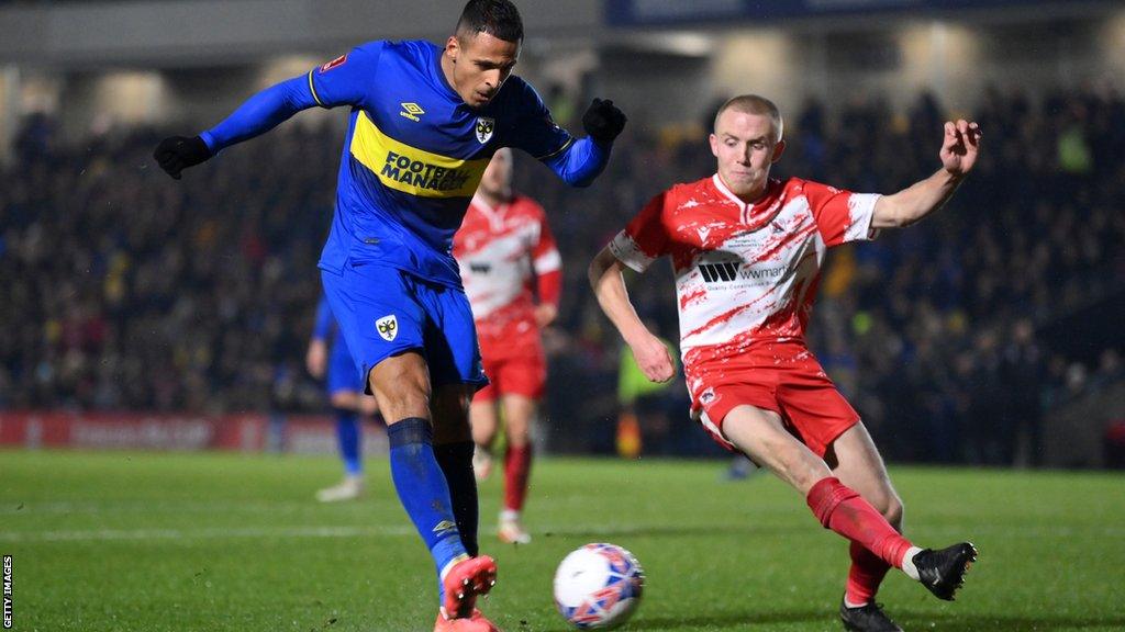 Ali Al-Hamadi of AFC Wimbledon shoots under pressure from Benedict Bioletti of Ramsgate during the Emirates FA Cup Second Round match between AFC Wimbledon and Ramsgate