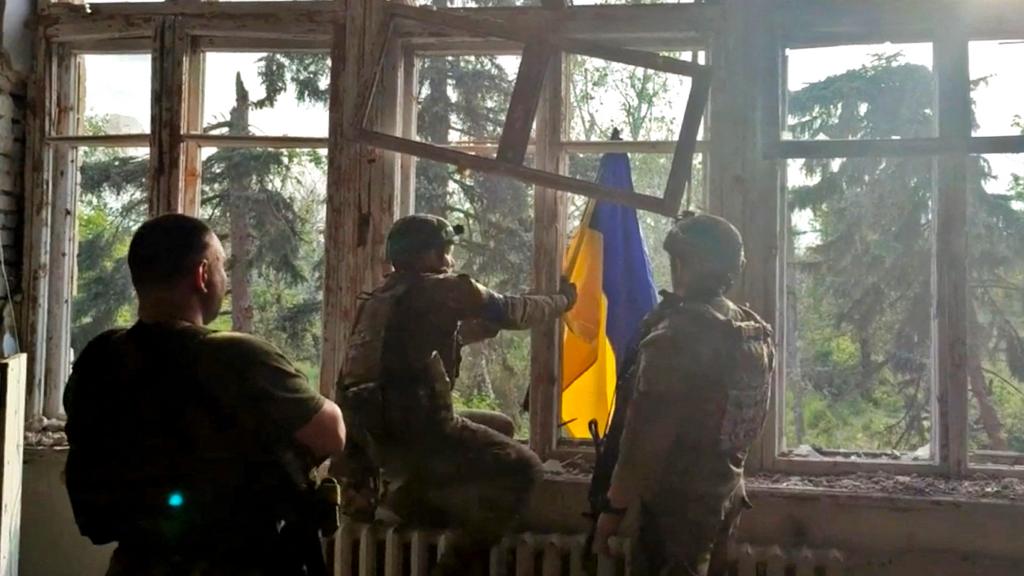 Ukrainian soldiers place a Ukrainian flag at a building, during an operation that claims to liberate the first village amid a counter-offensive, in a location given as Blahodatne, Donetsk Region, Ukraine, in this screengrab taken from a handout video released on 11 June 2023