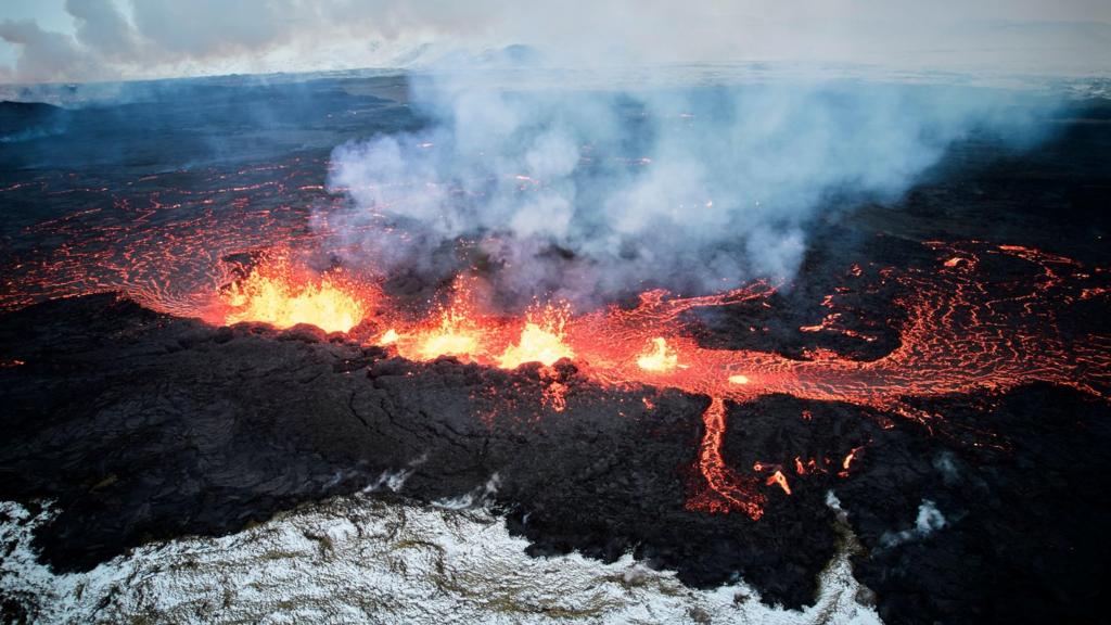 An aerial view taken with a drone shows lava and smoke spewing from a volcanic fissure during an eruption, near the town of Grindavik, in the Reykjanes peninsula, southwestern Iceland, 19 December 2023.