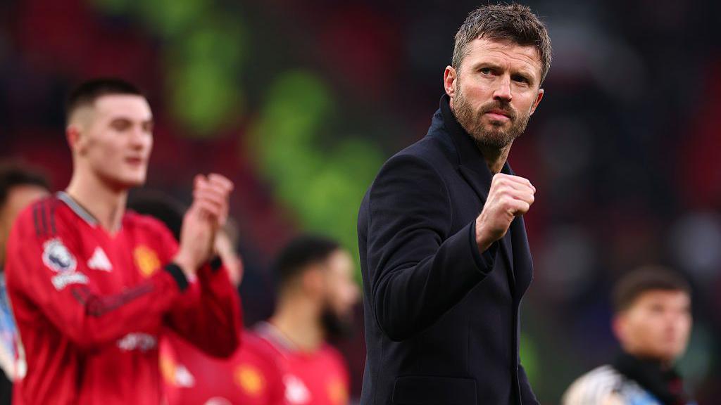 Michael Carrick clenches his fist towards the crowd, with Benjamin Sesko out of focus behind him