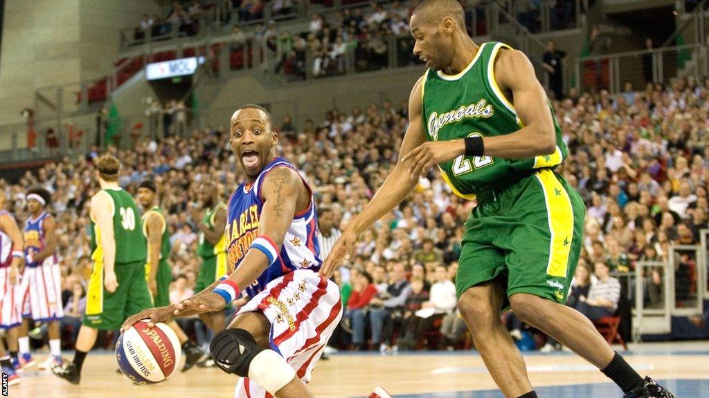 A gurning Harlem Globetrotter dribbles around Washington Generals' Antoine Maddox