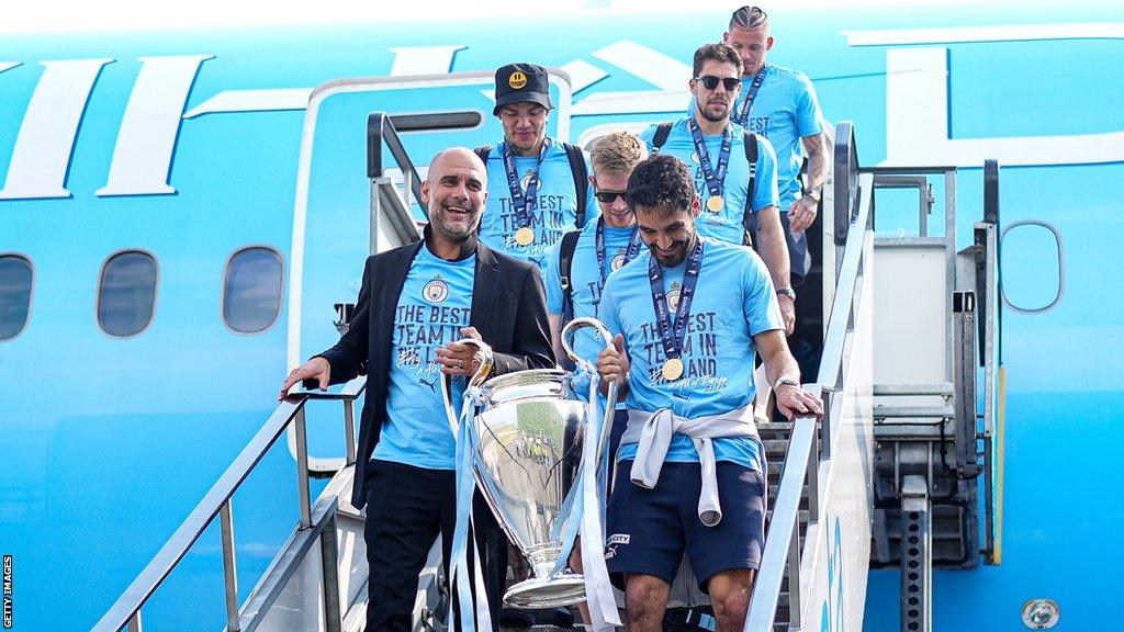 Pep Guardiola and Ilkay Gundogan lead the Manchester City team off the plane holding the Champions League trophy