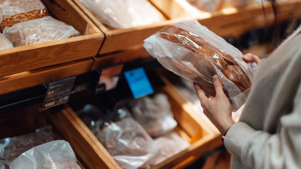 A woman holds bread in a supermarket