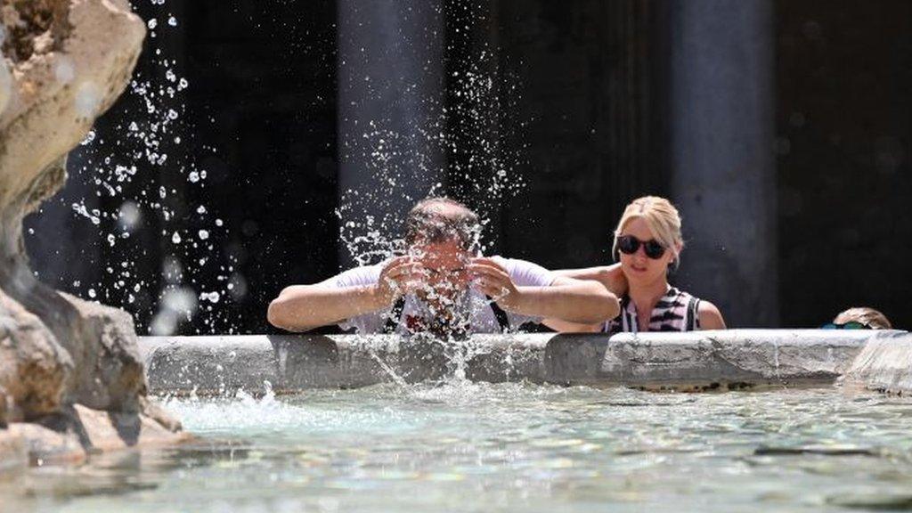 A man cools off with some water out of a fountain