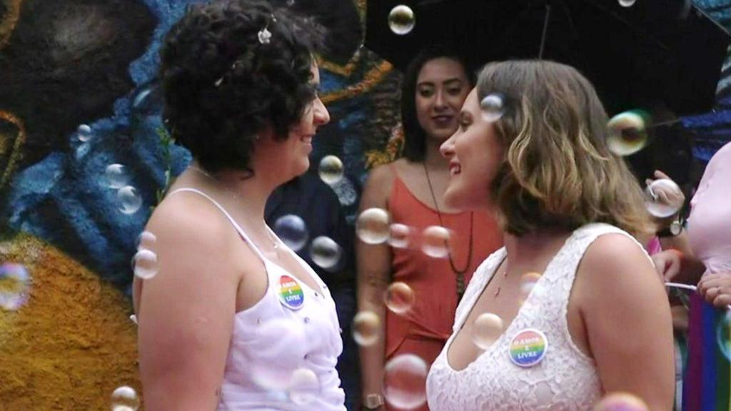 Two women in wedding dresses celebrate on wedding day