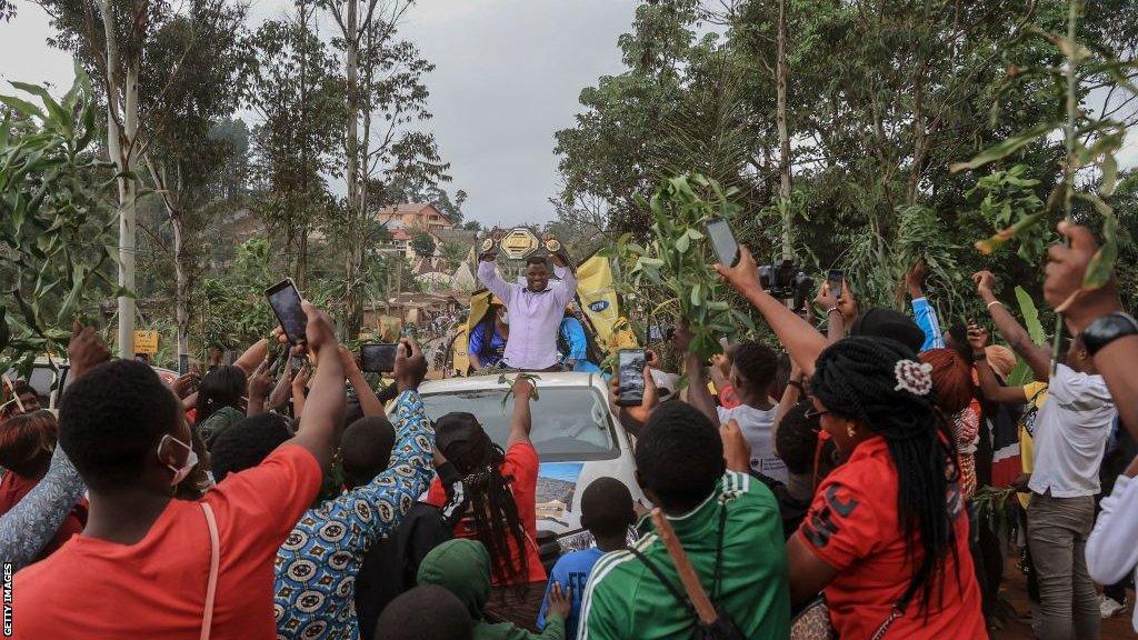 Francis Ngannou is surrounded by people as he presents his UFC belt in Cameroon