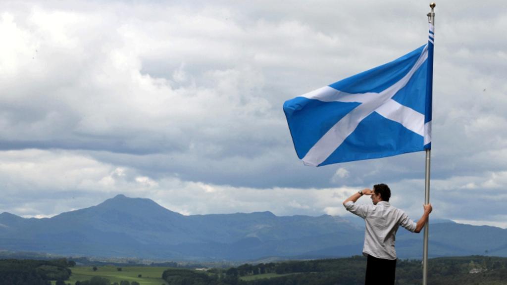 Man looking over mountains holding a saltire