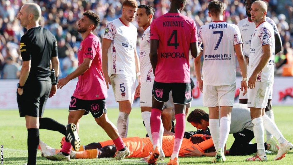 Mory Diaw receives treatment on the field as team-mates and rival players stand around