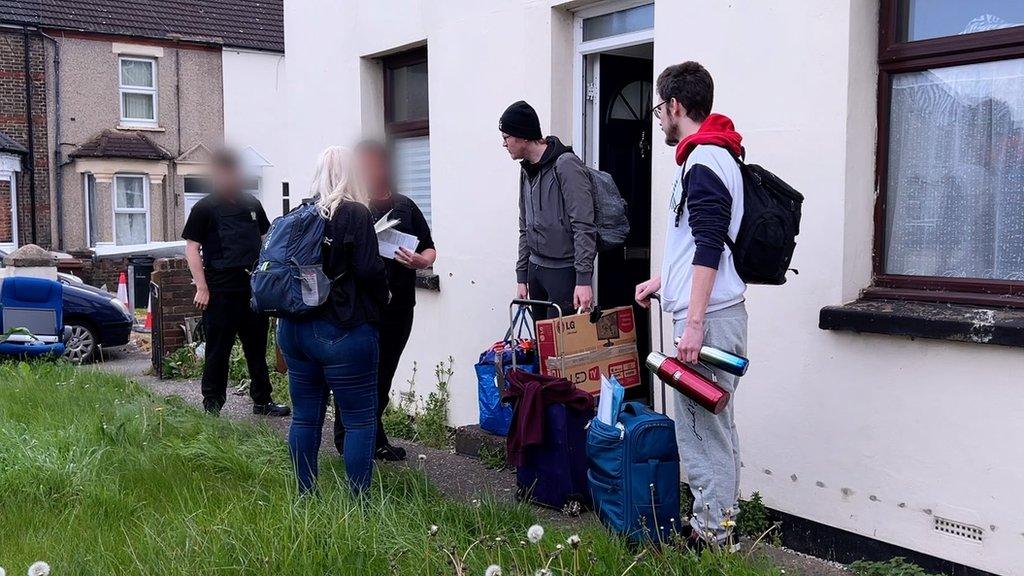 Heidi Dodson and her two sons receiving an eviction notice from two bailiff officers.