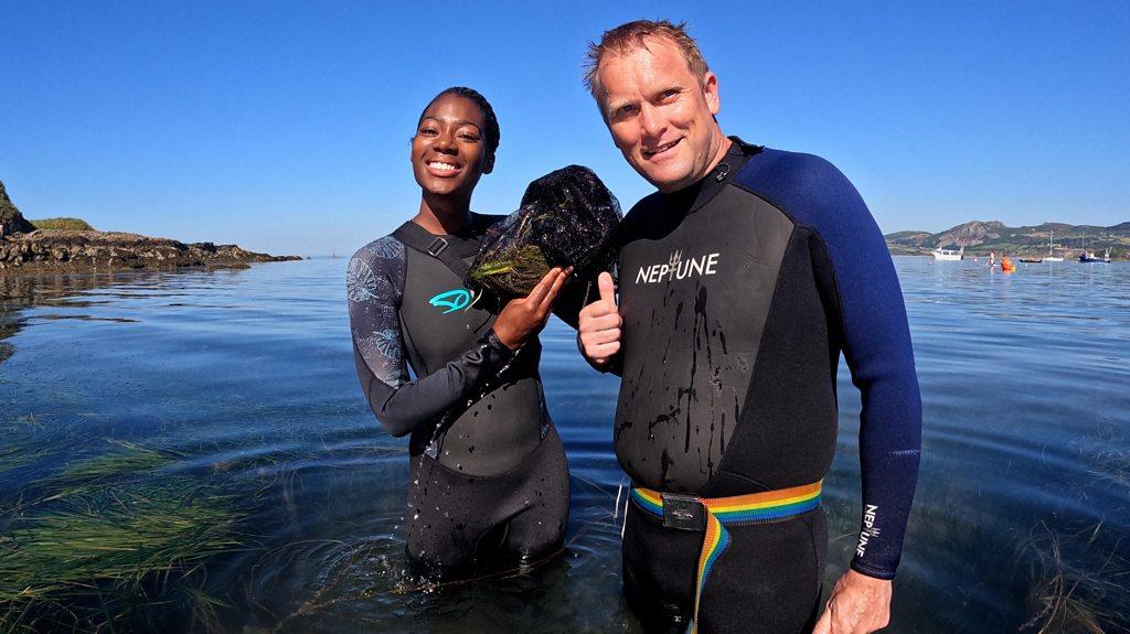 newsround-presenter-shanequa-paris-and-project-seagrass-scientist-richard-unsworth-standing in the sea-in-a-welsh-bay