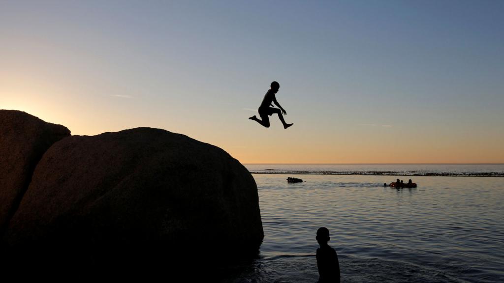 A child leaps leaps into a tidal pool as temperatures soar at Camps Bay beach in Cape Town, South Africa - 11 December 2016