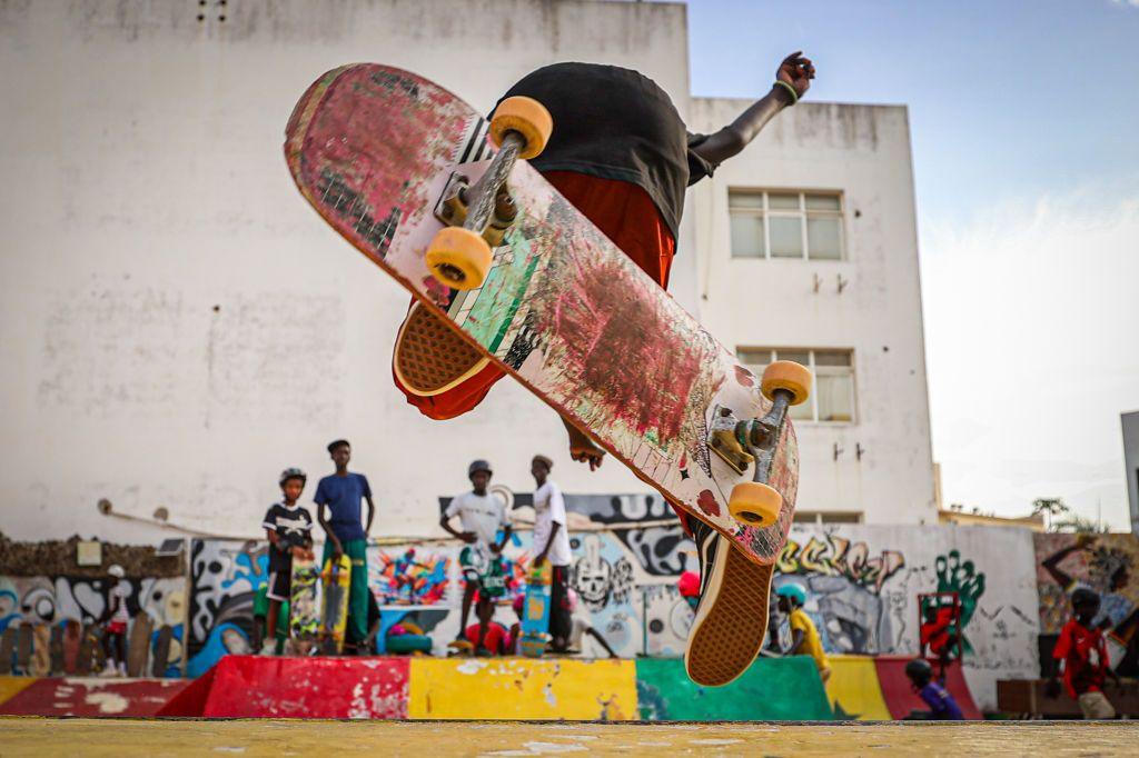 A young skateboarder performs a flip in the air while others look on.