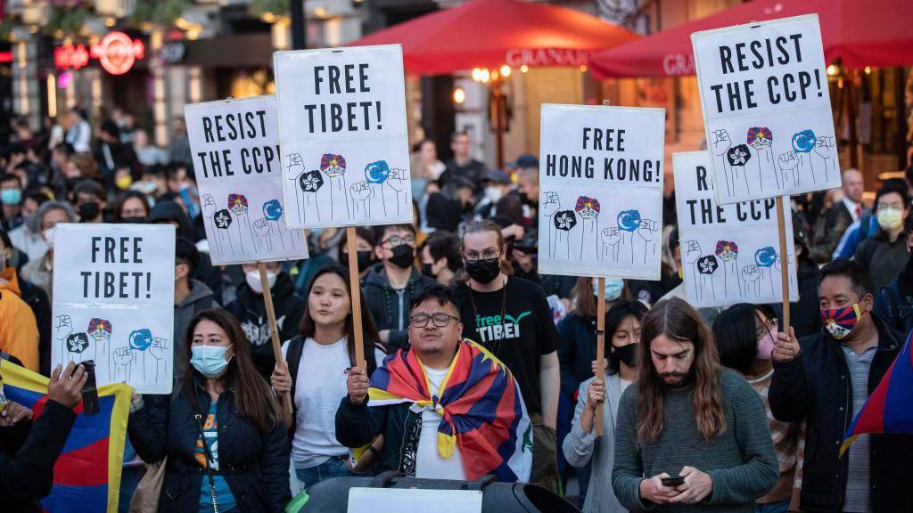 A group of protesters holding signs saying "Free Tibet" and "Free  Hong Kong" in London