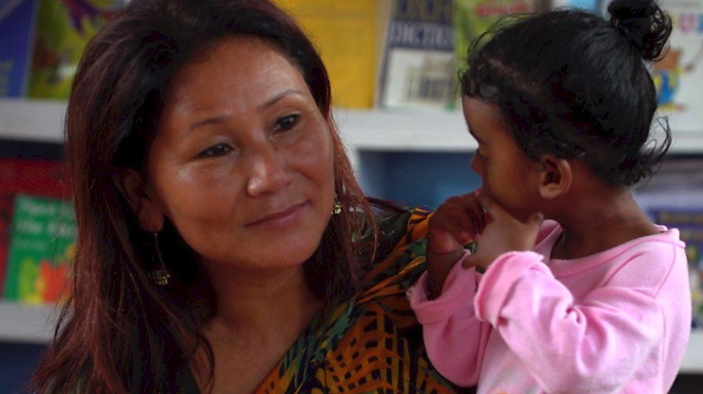 Indira Ranamagar hold a child in a classroom